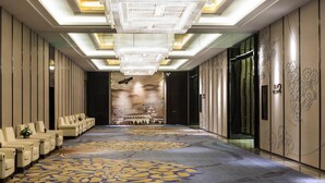 A hotel lobby with a long row of seating, a large chandelier, and a decorative wall mural. - Pullman Weifang (Weifang)