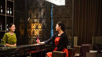 A bar area with a patterned wall, a chandelier, and a bar counter.