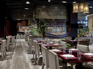 A restaurant with long tables, chairs, and a decorative boat centerpiece. - Pullman Weifang (Weifang)