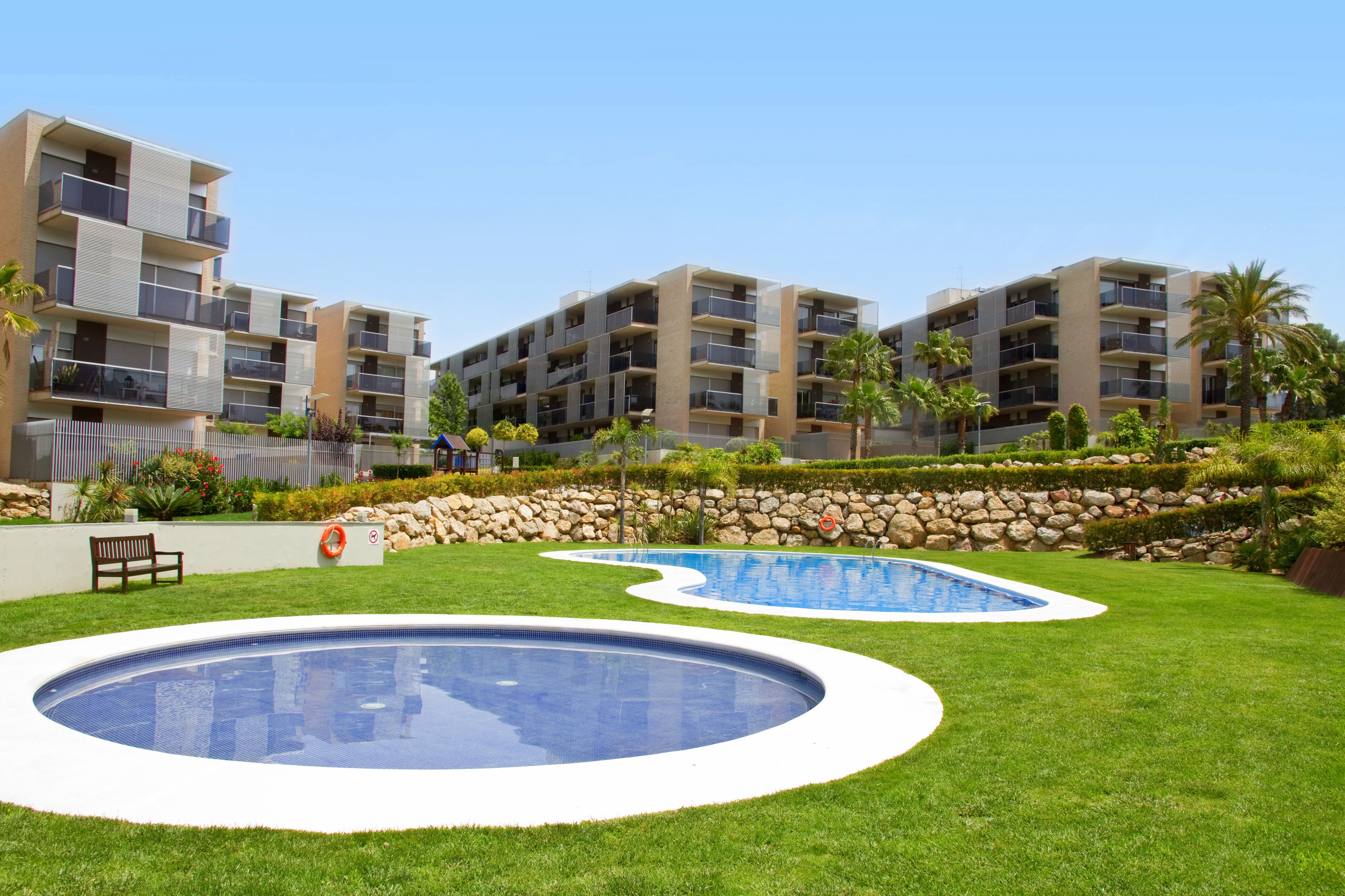 A residential building with multiple balconies, a swimming pool, and a well-maintained lawn.