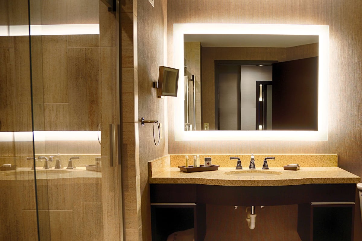 A modern bathroom with a large mirror, dual sinks, and a glass shower enclosure.