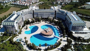 A large hotel with a central swimming pool, multiple balconies, and surrounding greenery. - Amelia Beach Resort Hotel & Spa (Manavgat)
