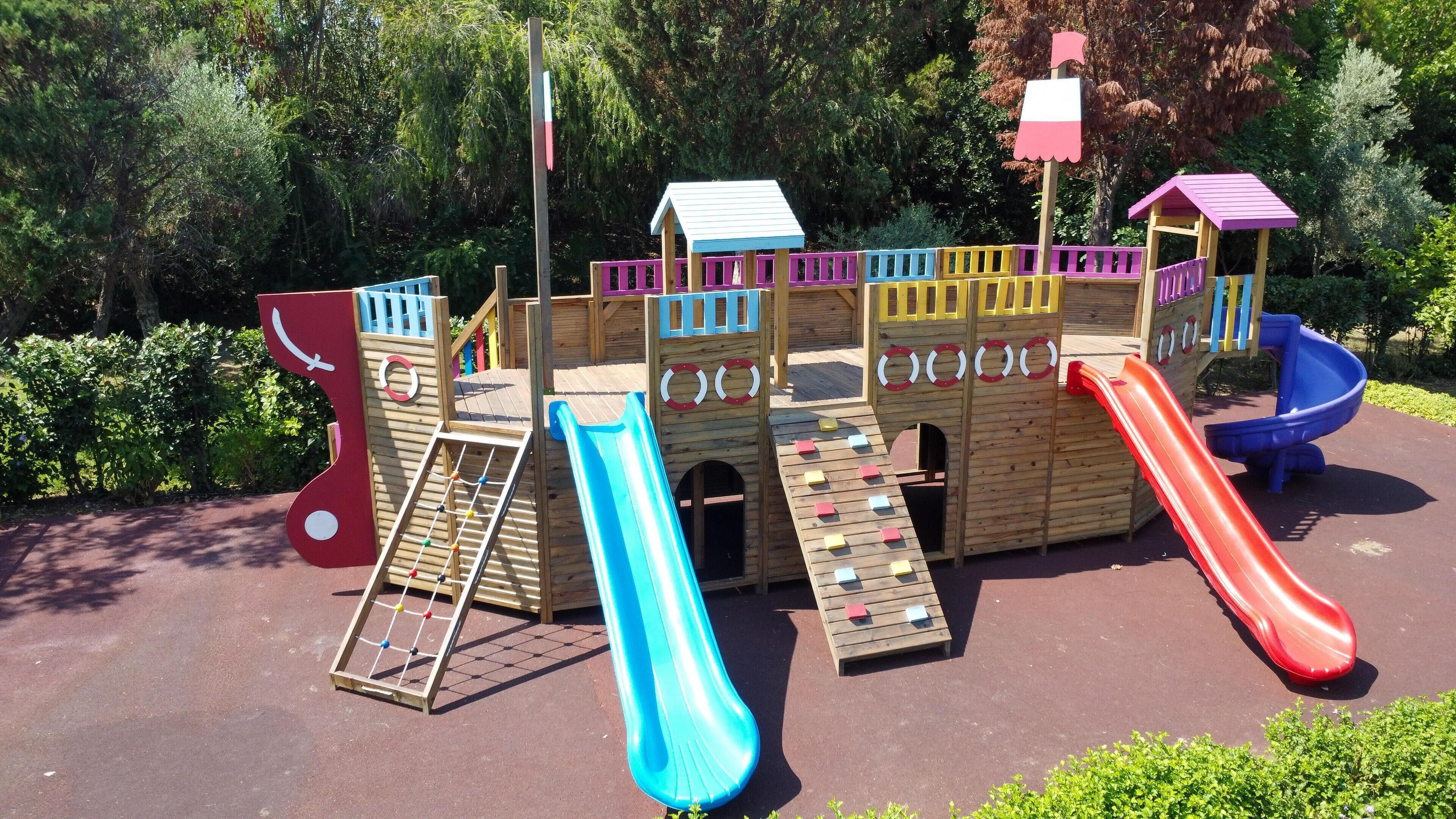 A wooden play structure with multiple slides and climbing elements.