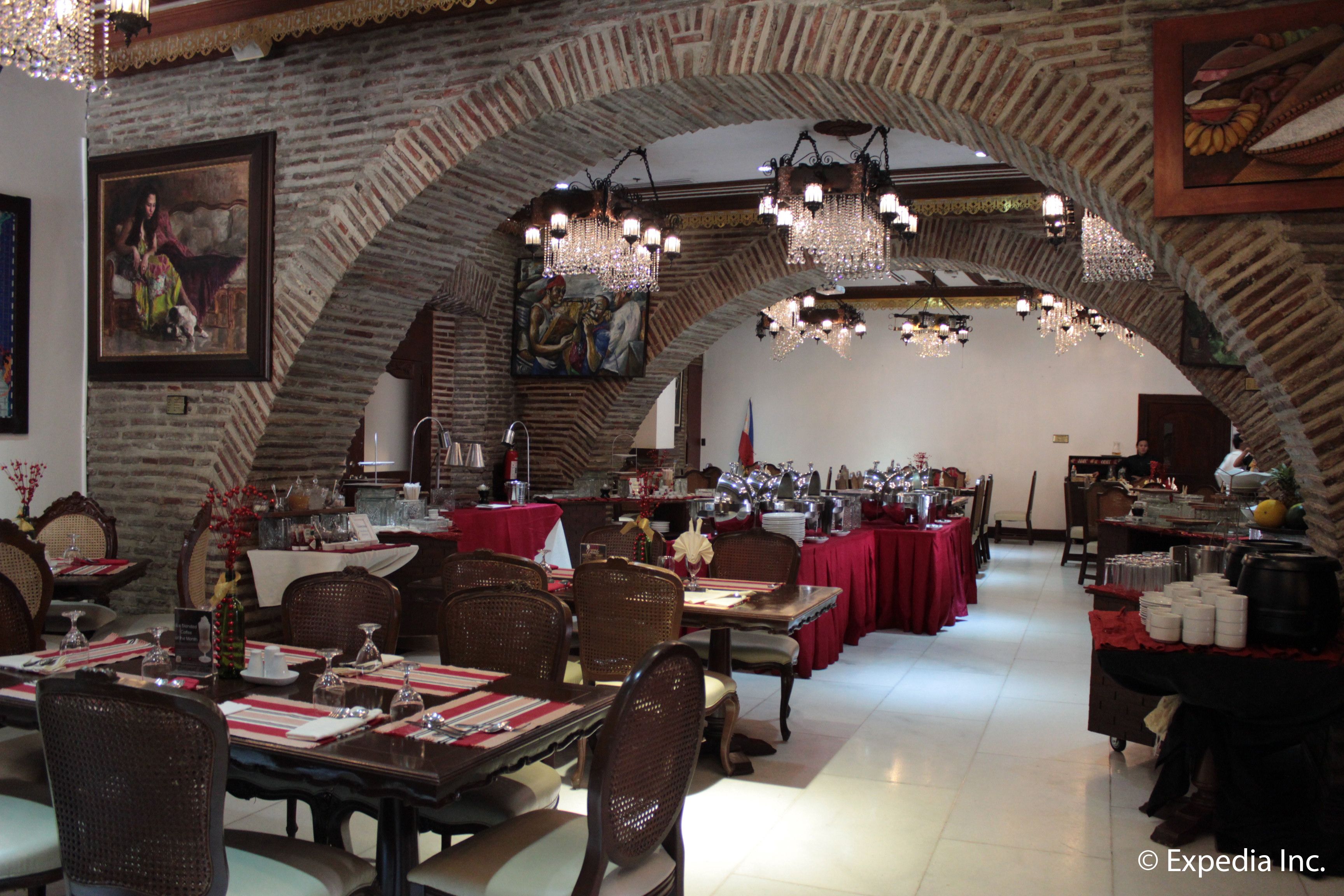A restaurant with brick arches, chandeliers, and red tablecloths.