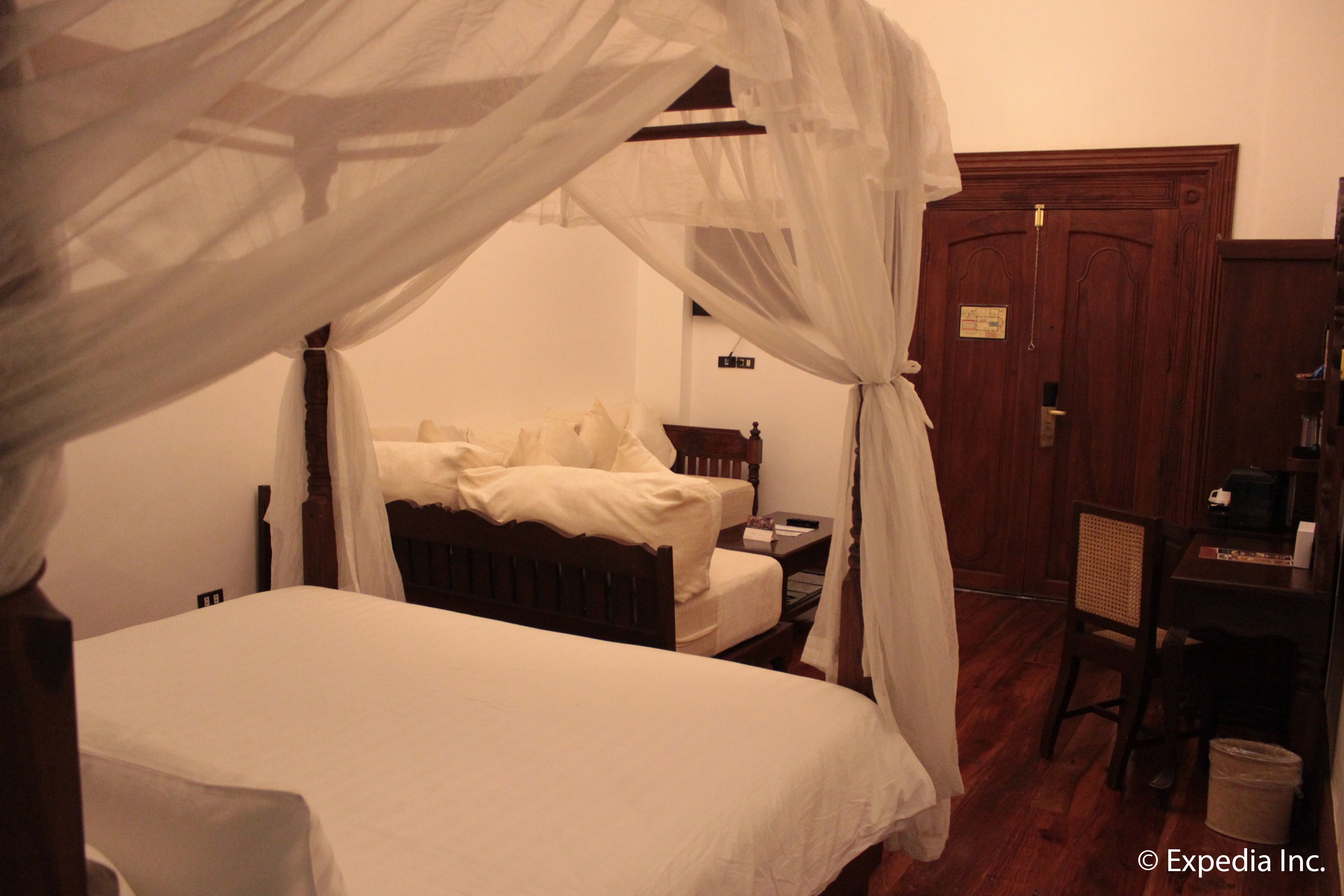 A bedroom with a four-poster bed, a wooden desk, and a chair.