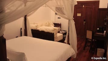 A bedroom with a four-poster bed, a wooden desk, and a chair.