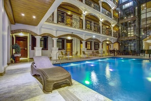 An indoor swimming pool with a lounge chair, multiple balconies, and ornate architectural details. - Hotel Luna (Vigan)