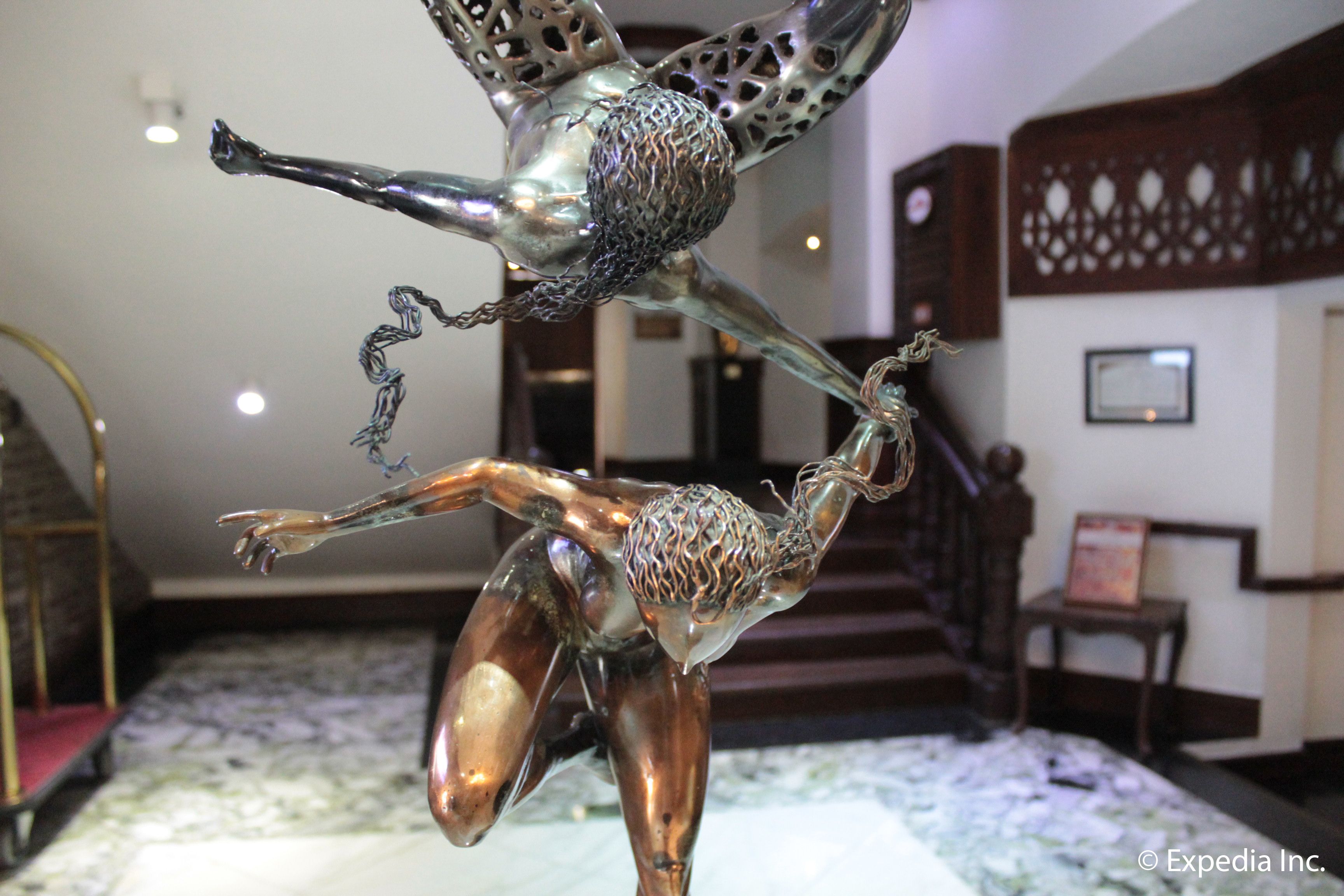 A room with a bed, a staircase, and a decorative metal sculpture.