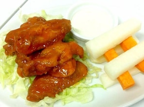 A plate with chicken wings, lettuce, and carrot sticks. - Hotel Luna (Vigan)