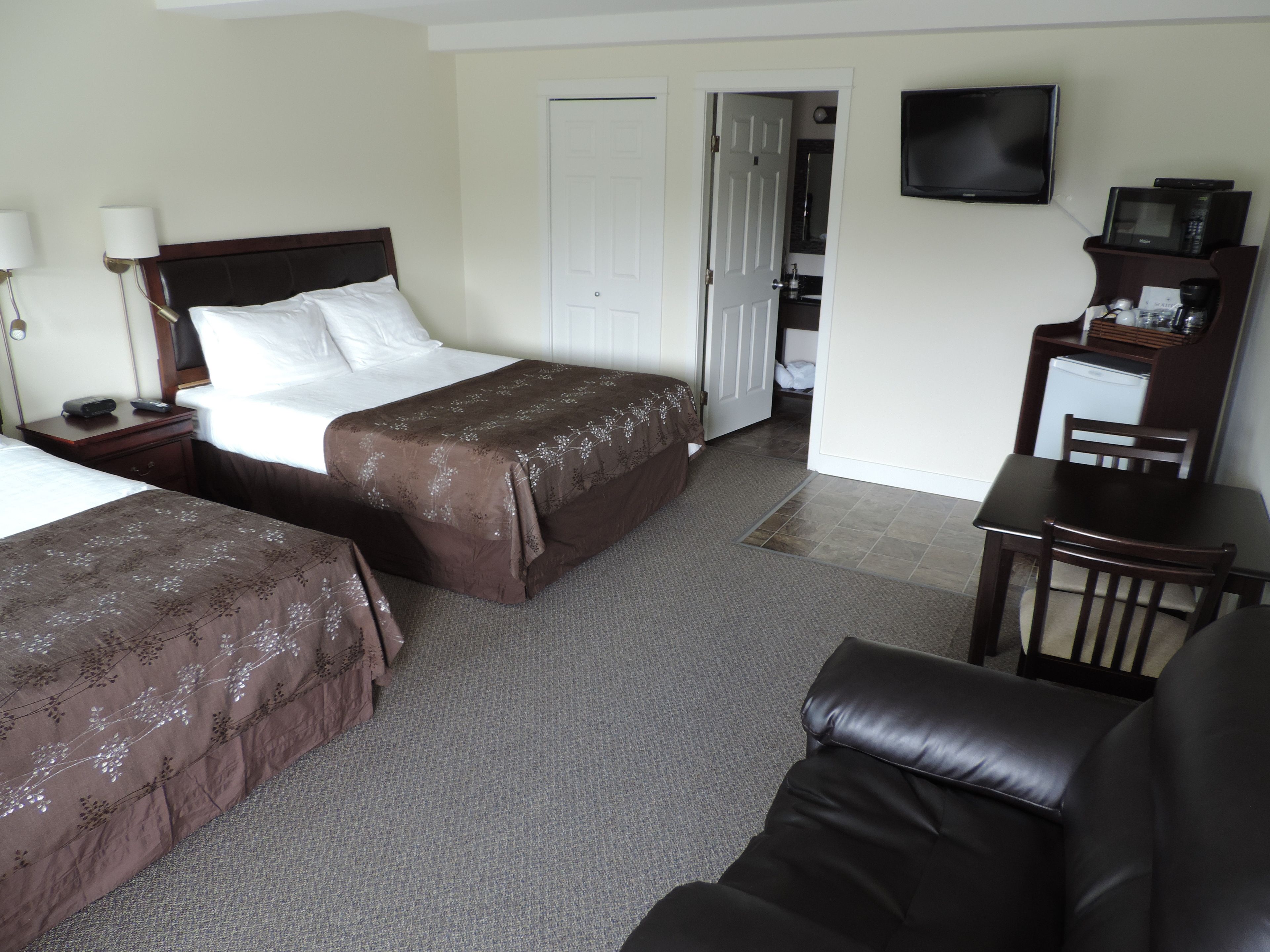 A hotel room with two beds, a TV, a desk, and a chair.