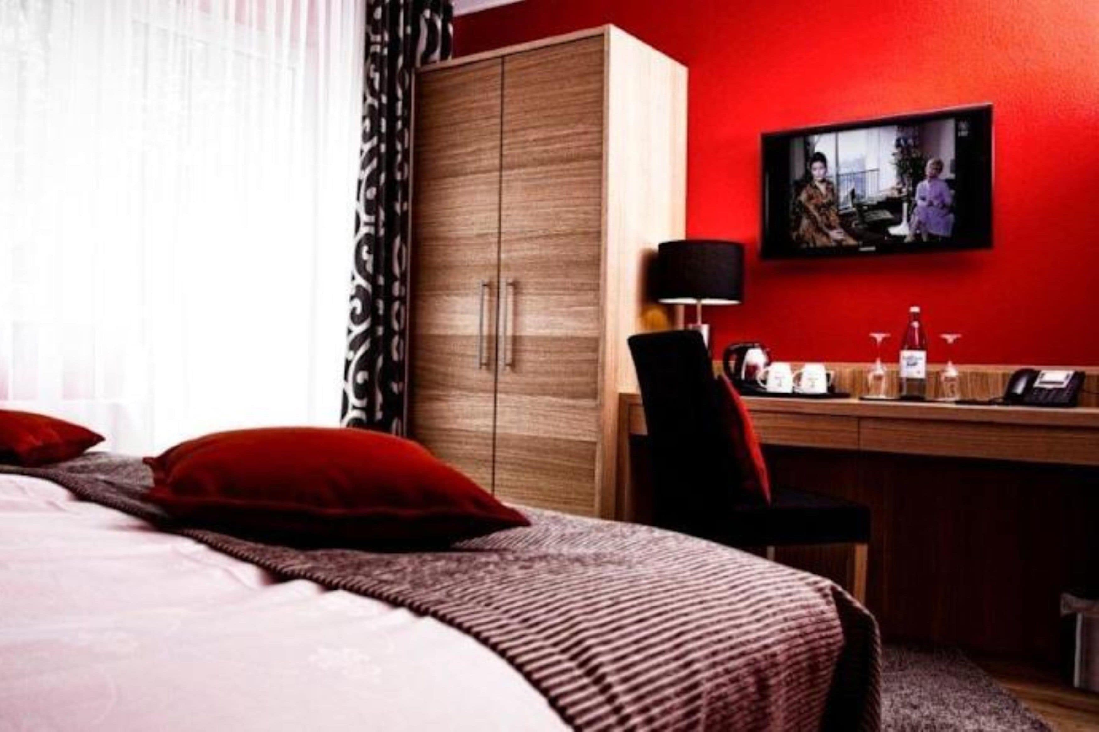 Une chambre d’hôtel équipée d’un lit, d’un bureau, d’une télévision et d’une armoire.