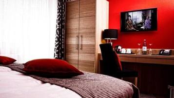 A hotel room with a bed, a desk, a television, and a wardrobe.