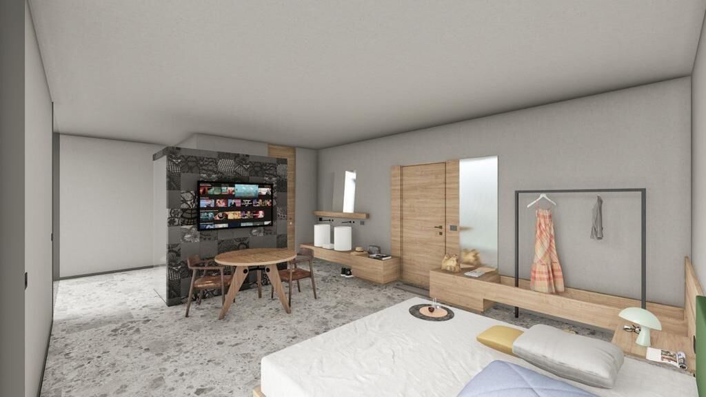 A modern bedroom with a bed, a desk, a chair, a wardrobe, and a TV mounted on a stone wall.