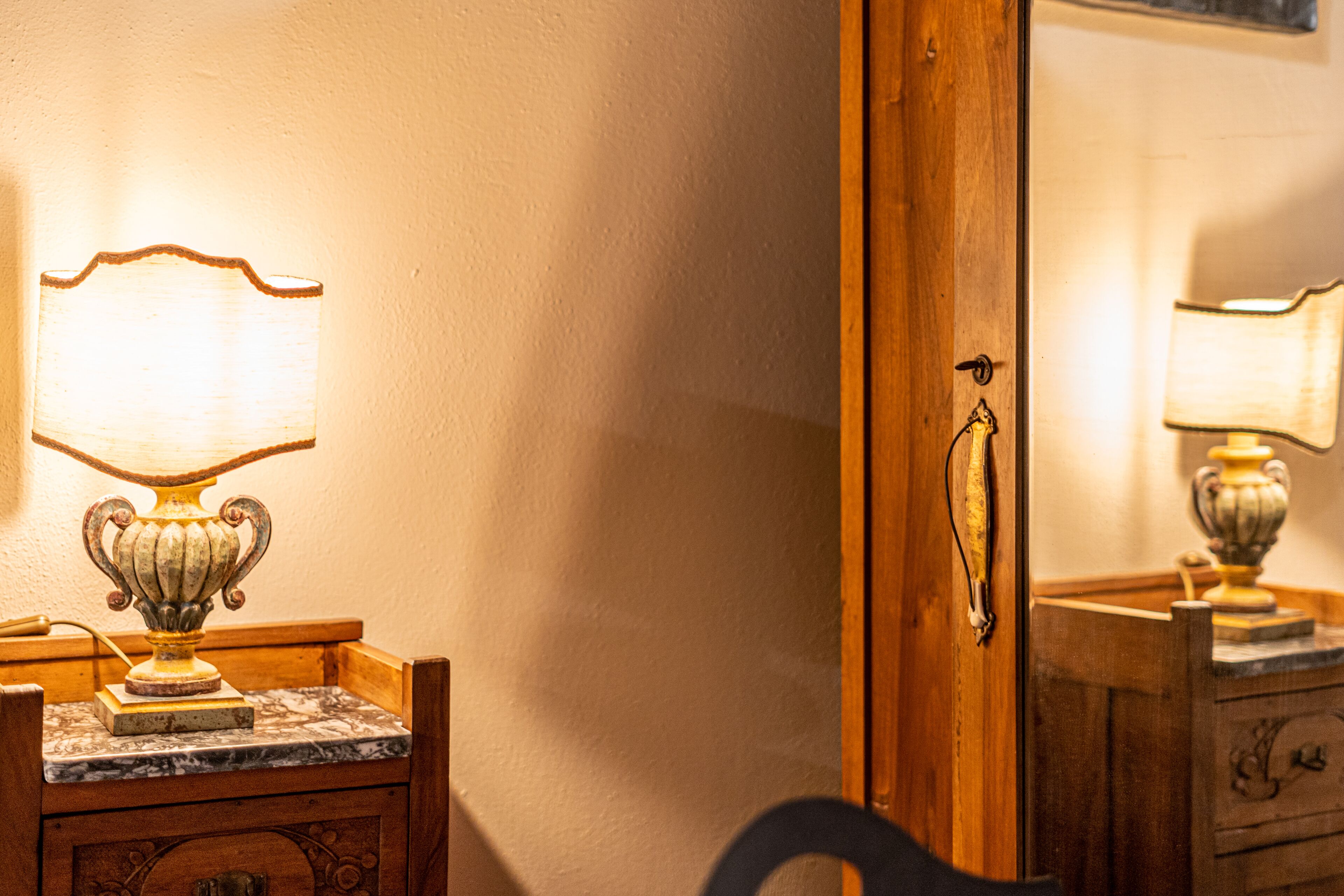 A wooden dresser with a marble top and a lamp on it.
