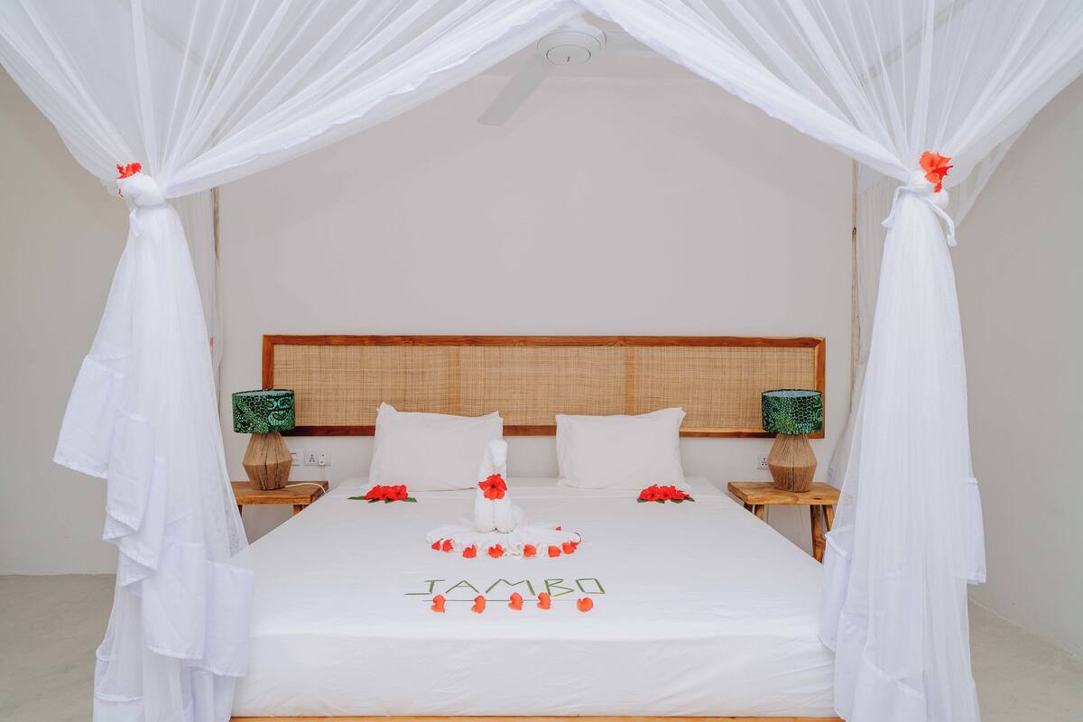A neatly made bed with a canopy, two bedside tables with lamps, and a headboard.