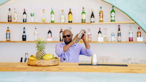 A bar area with shelves of liquor bottles, a pineapple, and a bar counter.