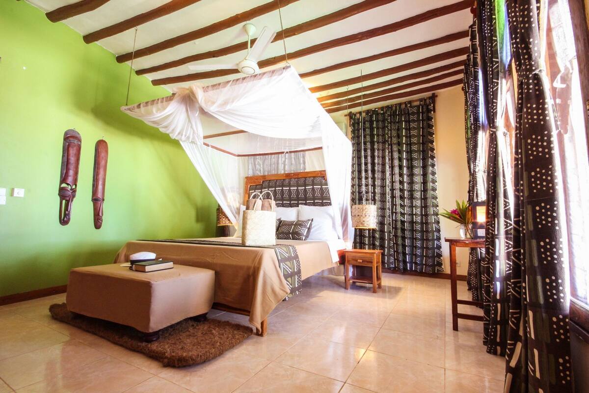 A bedroom with a bed, bedside table, and a canopy bed.