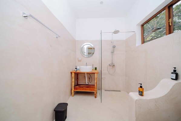 A modern bathroom with a wooden vanity, a glass shower enclosure, and a window providing natural light. - Spice Island Hotel & Resort (Jambiani)
