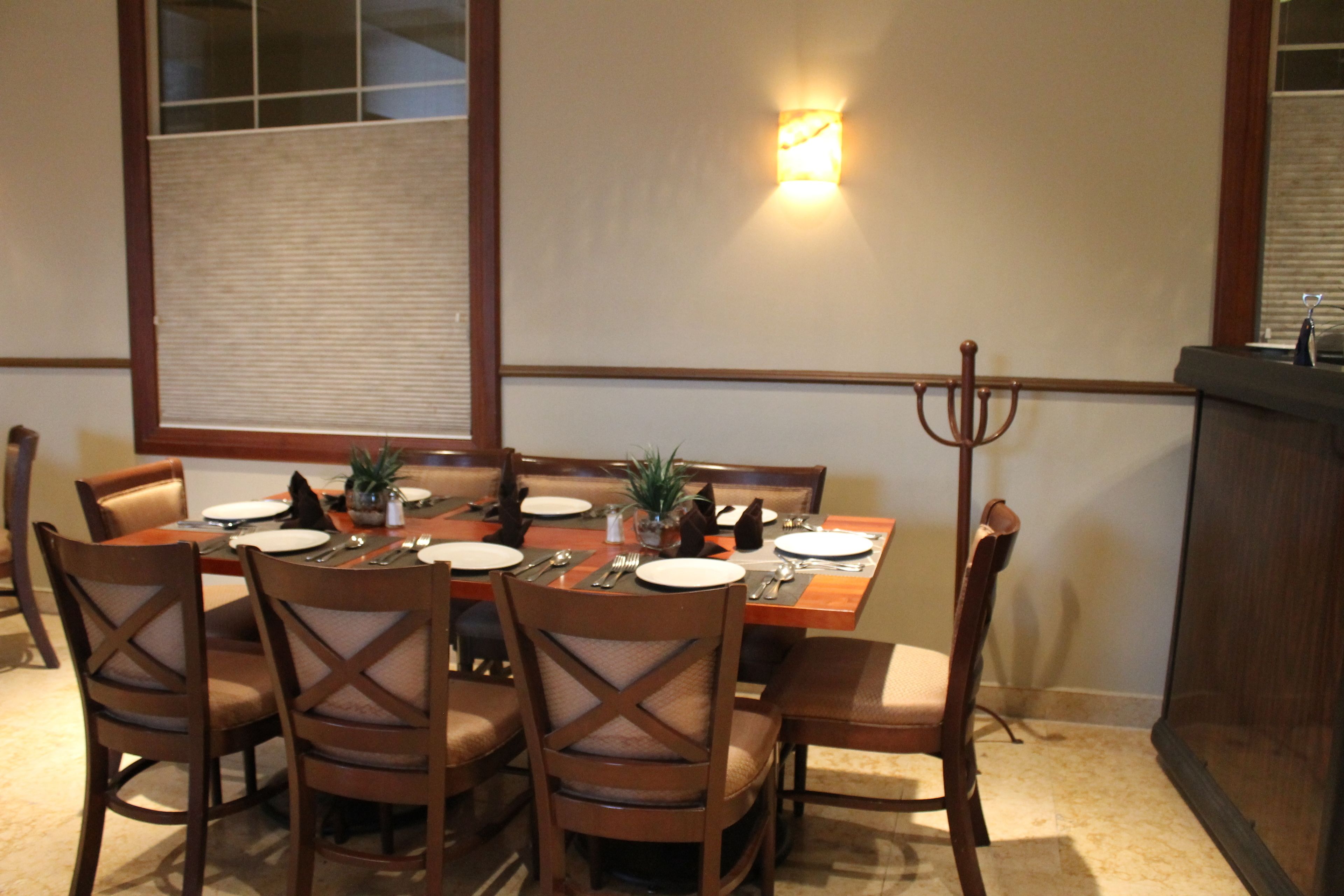 Un comedor con una mesa dispuesta para seis personas, rodeada de sillas de madera con asientos acolchados.