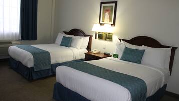 Two twin beds with matching headboards, a bedside table with a lamp, a framed picture on the wall, and a window with curtains.