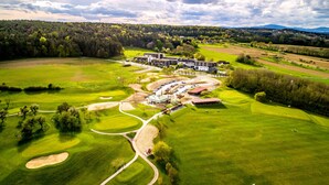 Ein Golfplatz mit Clubhaus, Parkplätzen und umliegenden Grünflächen.