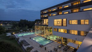Ein modernes Hotel mit Dachpool, Sitzgelegenheiten im Freien und großen Fenstern.