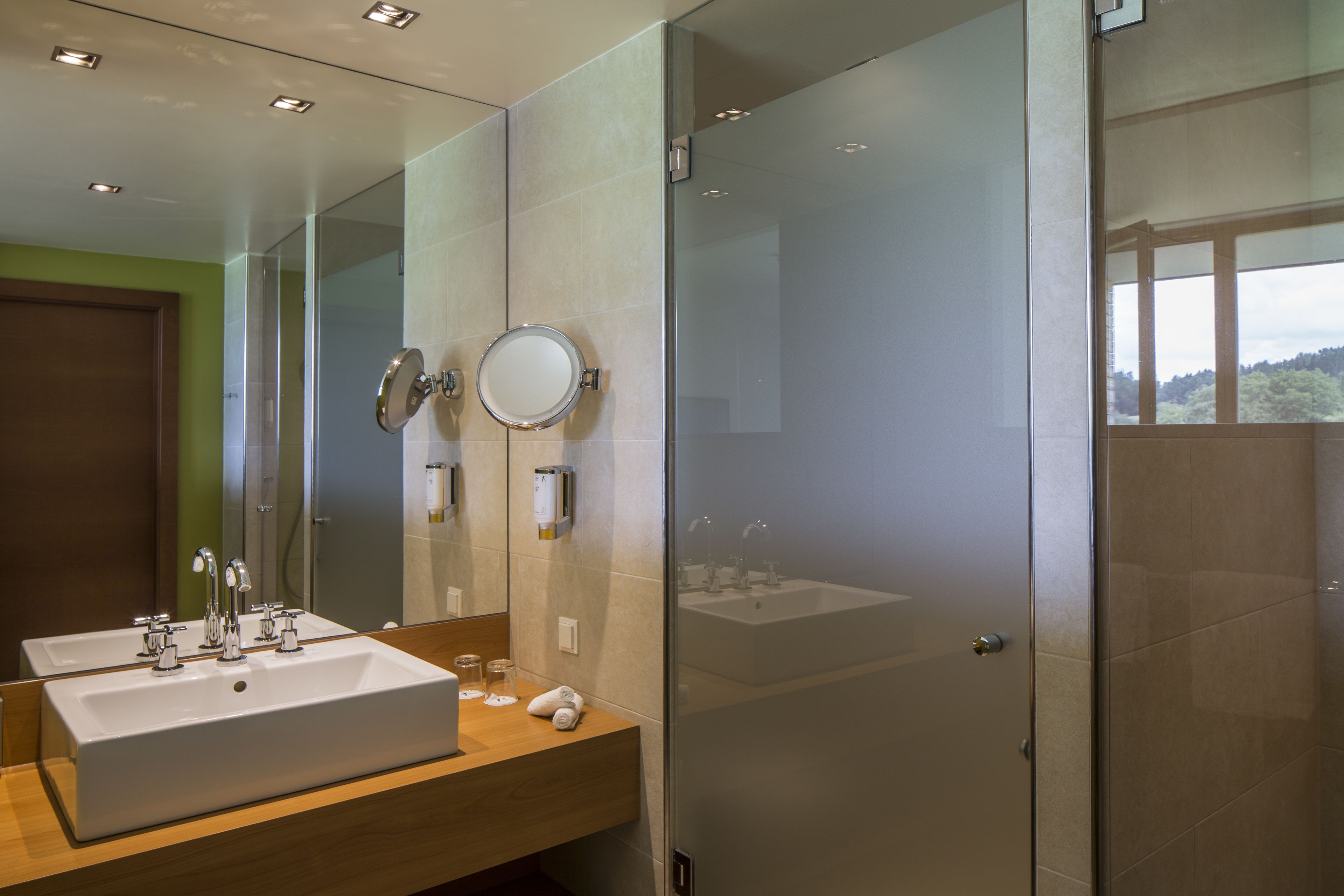 A modern bathroom with two sinks, a large mirror, and a glass shower enclosure.