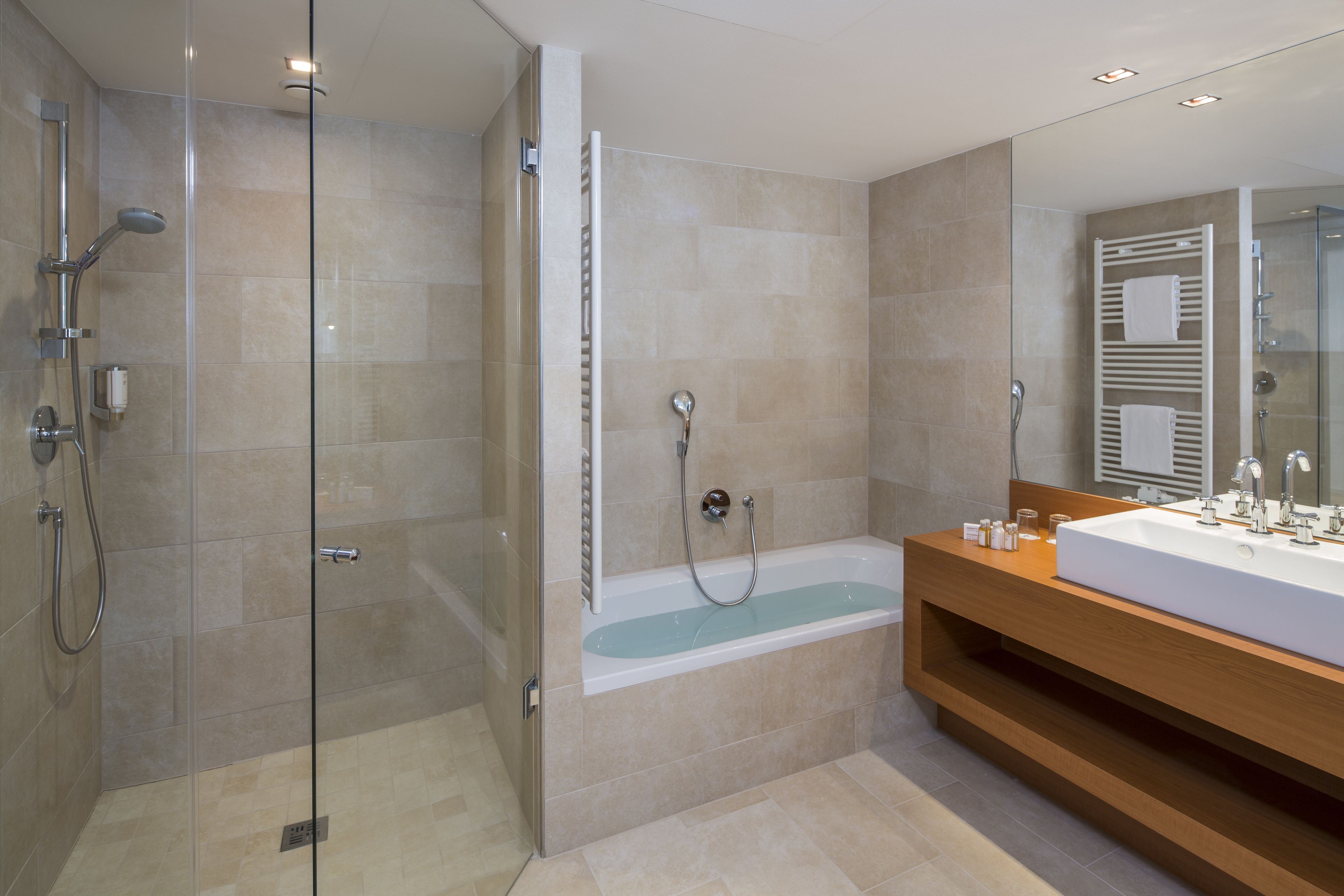 A modern bathroom with a glass-enclosed shower, a freestanding bathtub, and a wooden vanity with a large mirror.