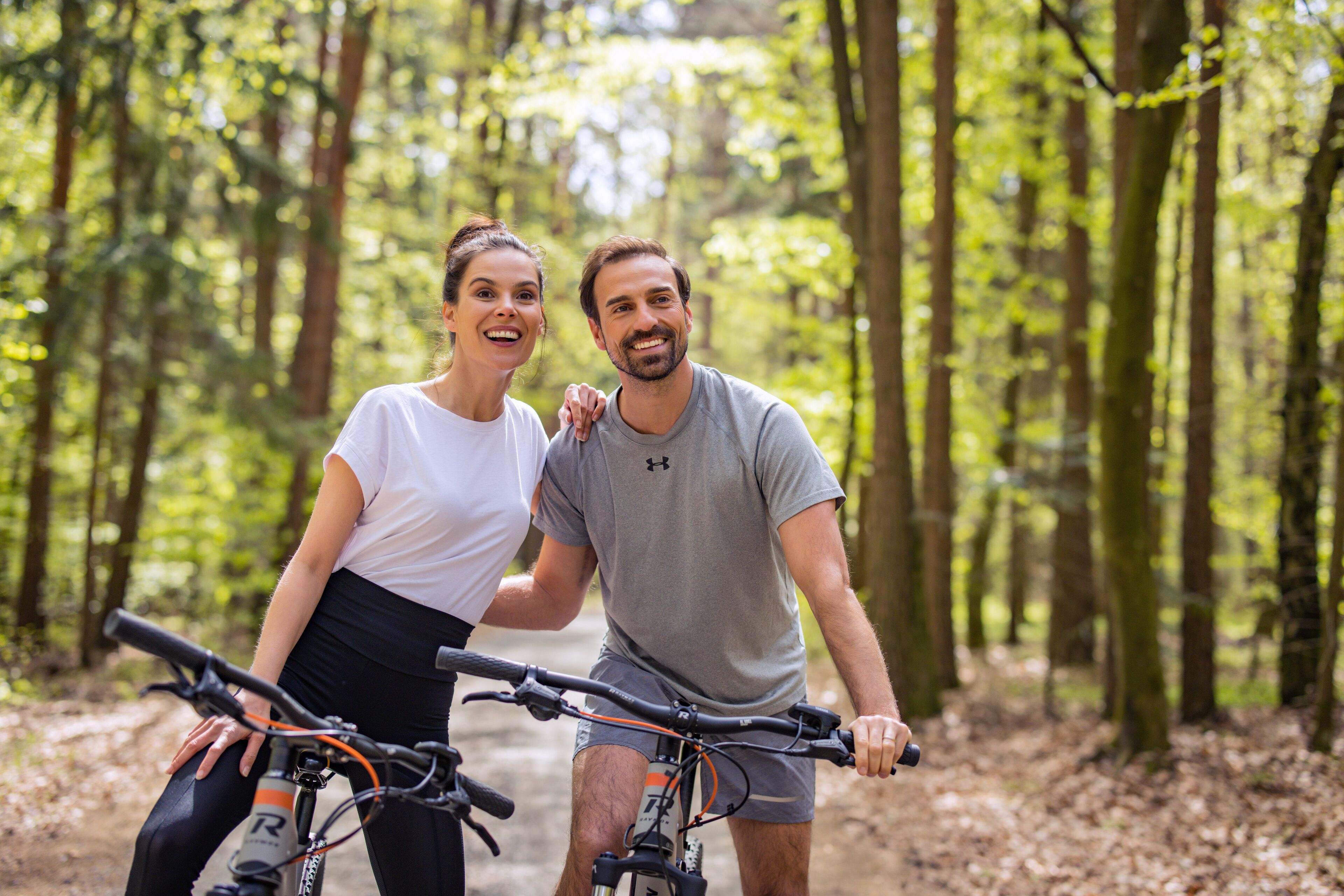 Dos personas en bicicleta en un área boscosa.