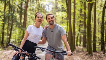 Dos personas en bicicleta en un área boscosa.