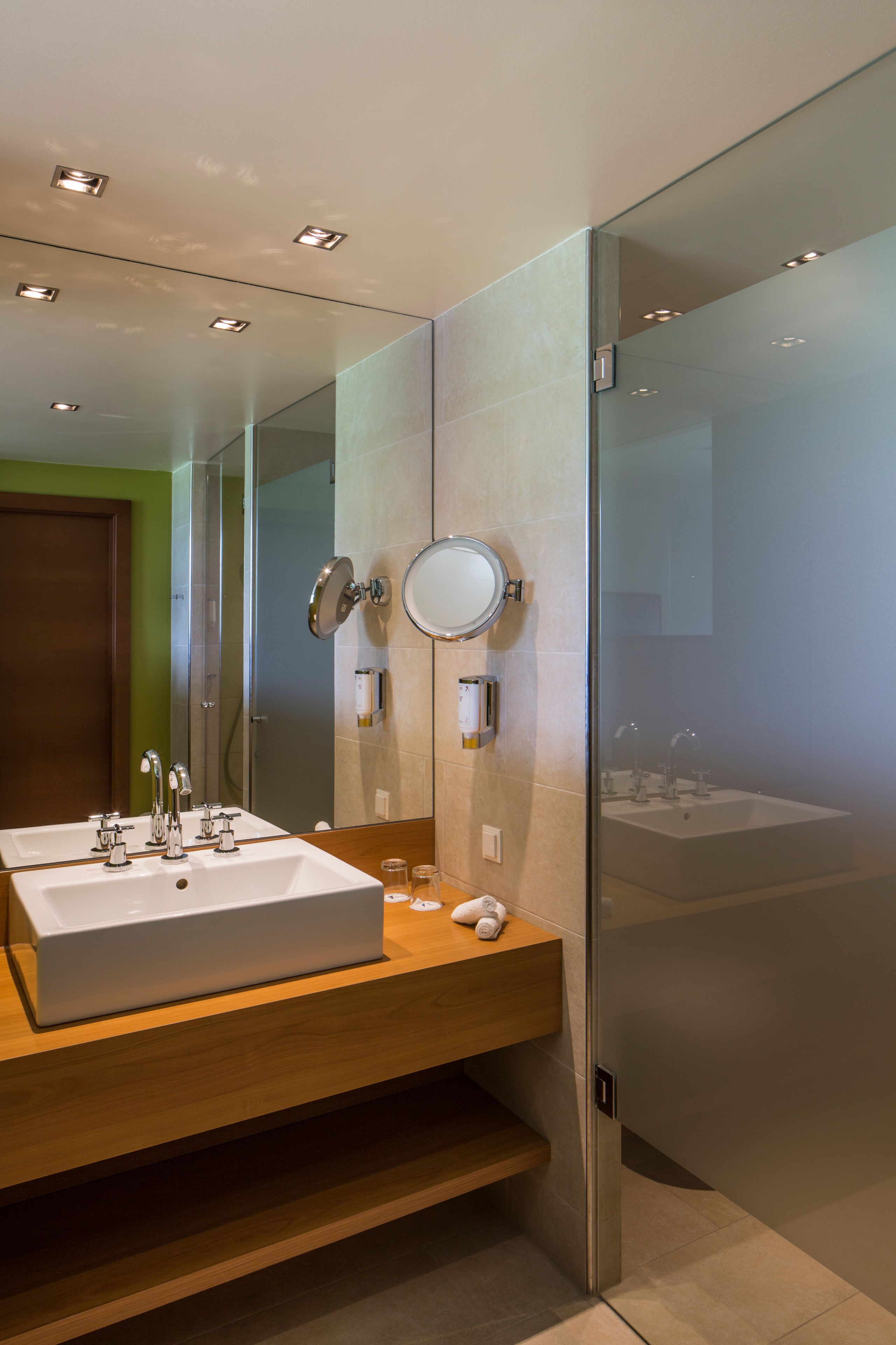 A modern bathroom with a large mirror, two sinks, and a glass shower enclosure.