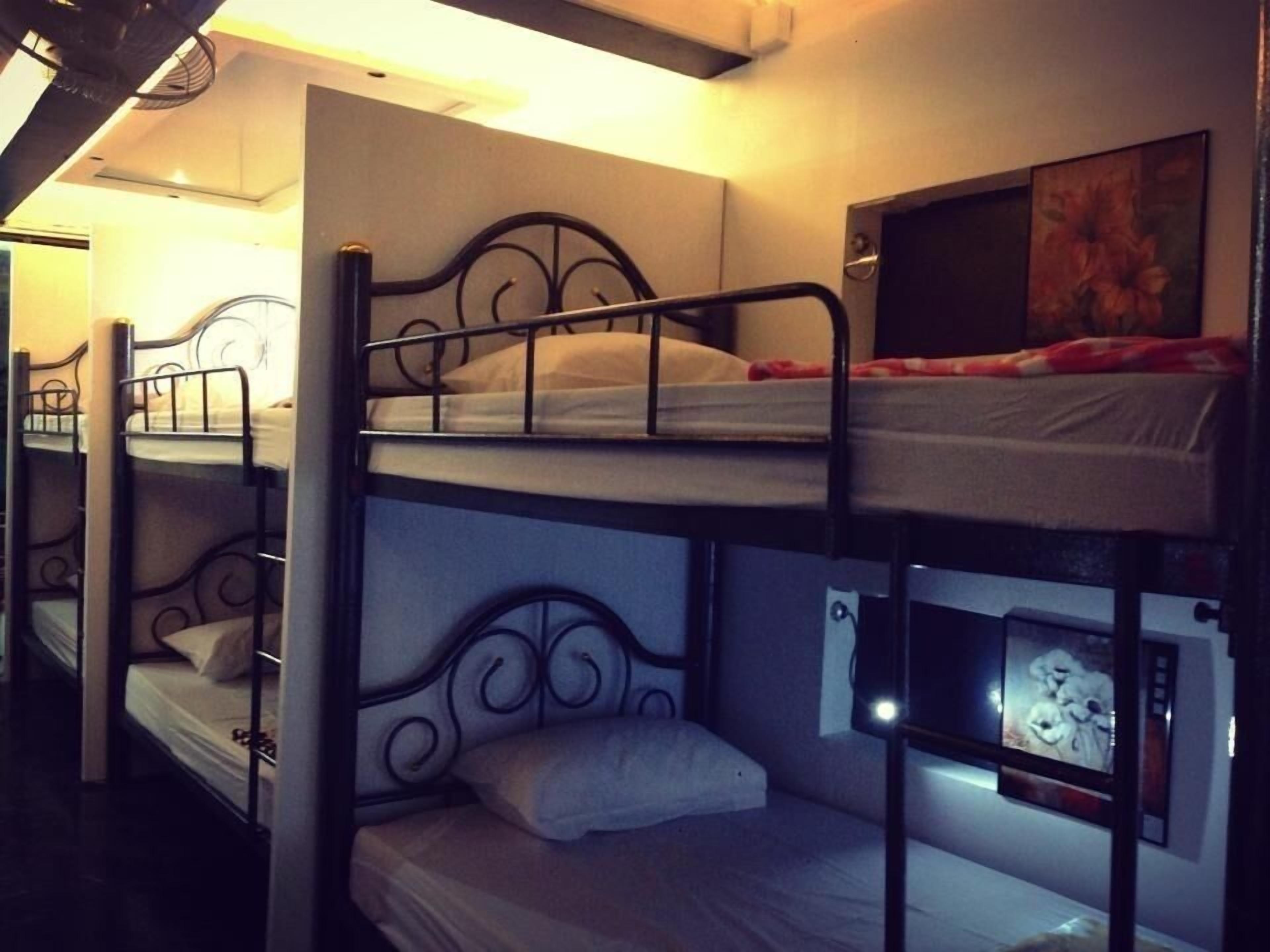 Une chambre avec un lit superposé, un téléviseur placé sur le lit du haut et une prise électrique sur le lit du bas.