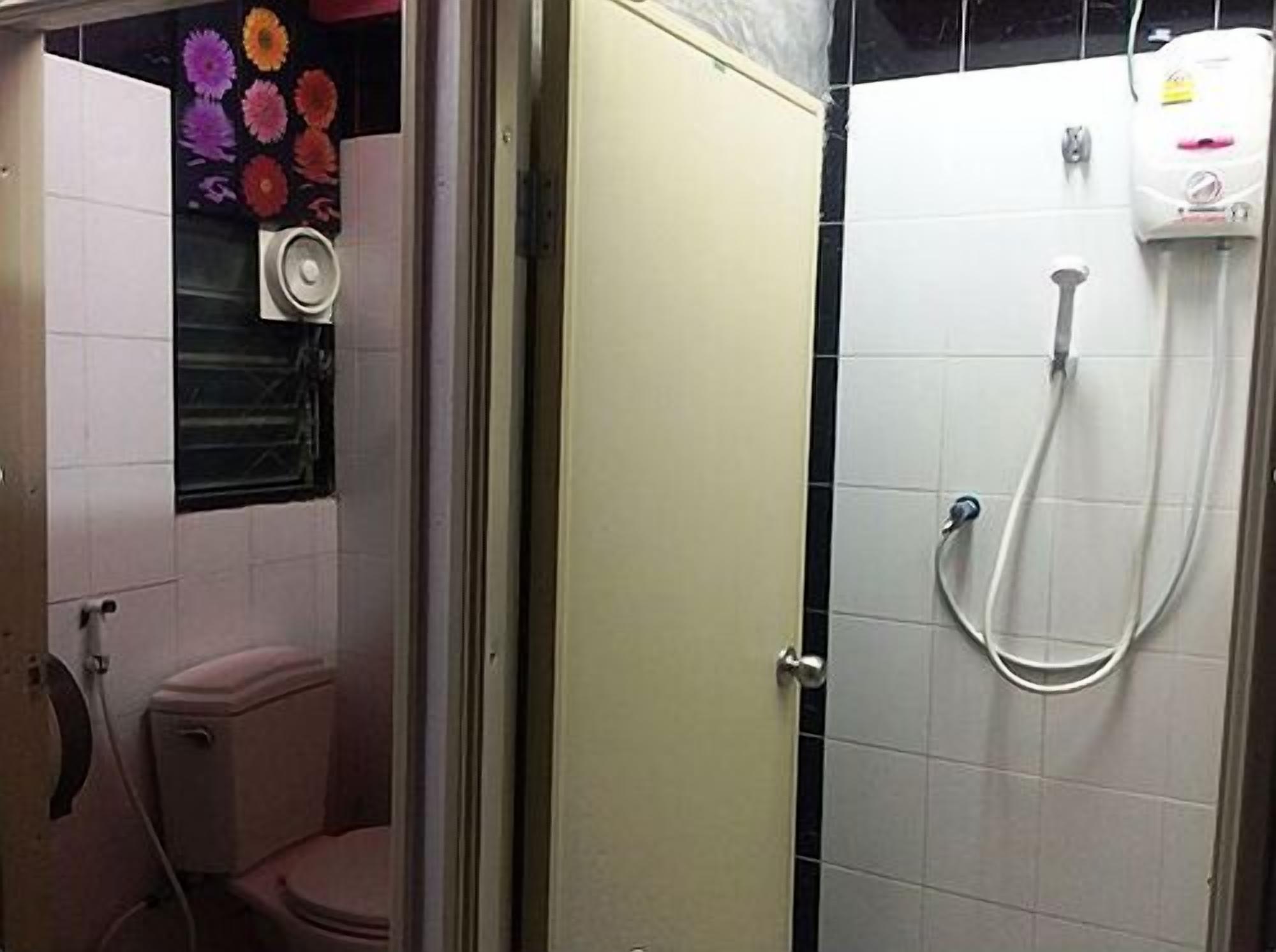 A bathroom with a toilet, a shower, and a wall-mounted toilet paper holder.