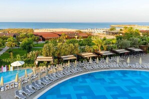 Um resort com piscina, espreguiçadeiras e vista para a praia.