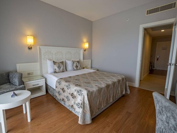 Una habitación de hotel con cama, mesitas de noche, una silla y un escritorio.