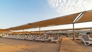 Area relax in spiaggia con lettini e ombrelloni.