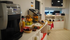 A breakfast buffet with a coffee machine, fruit, and various food items. - Hostal Aslyp 114 (Barcelona)