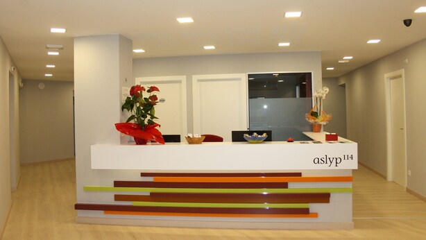 A reception desk with a modern design, featuring a nameplate and decorative items. - Hostal Aslyp 114 (Barcelona)