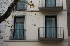 A building facade with three balconies, each with a wrought iron railing and a window. - Up Suites Bcn (Barcelona)