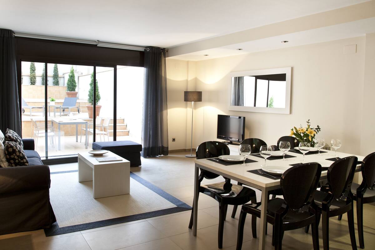 A modern living room with a sofa, a coffee table, and a dining area with a table set for four.