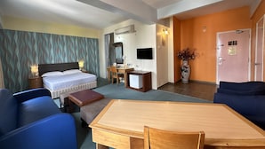 Ein Hotelzimmer mit Bett, Schreibtisch, Stuhl, Fernseher und Esstisch.