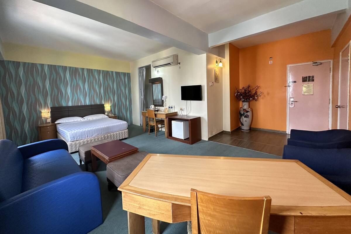 A hotel room with a bed, desk, chair, TV, and a dining table.