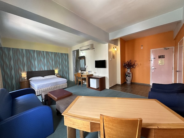 Een hotelkamer met een bed, bureau, stoel, televisie en een eettafel.