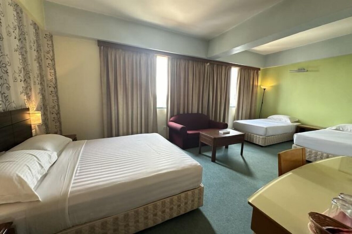A hotel room with a large bed, a smaller bed, a chair, a table, and a desk.