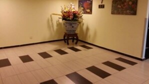 Ein Flur mit Fliesenboden, einer Blumendekoration auf einem Hocker und einem Schild mit der Nummer 7 an der Wand.