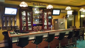 Eine Bar mit Theke, Barhocker und Regalen voller Flaschen.