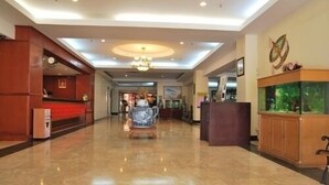 Eine geräumige Lobby mit Marmorboden, einer Rezeption, einer Kristallleuchtre und einem Aquarium.