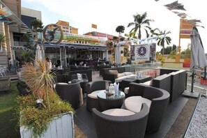An outdoor seating area with wicker furniture and a bar in the background. - Swings & Pillows - Histana I-City (Klang)