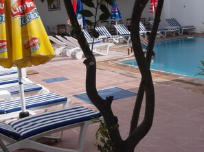 Una piscina al aire libre, sombrillas, tumbonas