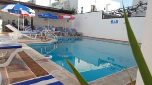 Una piscina al aire libre, sombrillas, tumbonas